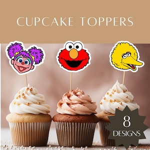 Puede incluir: Adornos para cupcakes con las caras de Abby Cadabby, Elmo y Big Bird en palitos de madera. El texto CUPCAKE TOPPERS aparece en la parte superior y una insignia oscura en forma de estrella con el texto 8 DESIGNS está en la esquina inferior derecha.