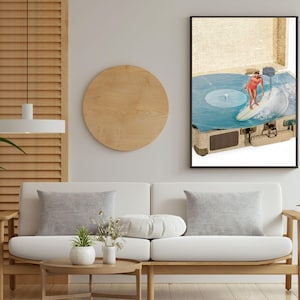 May include: A framed wall art print featuring a vintage suitcase open to reveal a blue vinyl record spinning on a turntable. A person in a red swimsuit is depicted surfing on a white surfboard across the surface of the blue vinyl record.