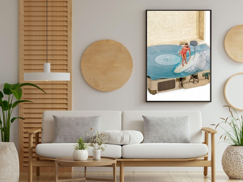 May include: A framed wall art print featuring a vintage suitcase open to reveal a blue vinyl record spinning on a turntable. A person in a red swimsuit is depicted surfing on a white surfboard across the surface of the blue vinyl record.
