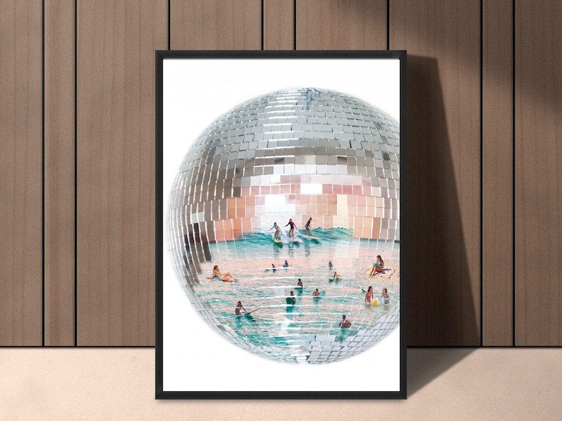 May include: A framed wall art print featuring a large, spherical disco ball with a mirrored surface. The interior of the sphere displays a surreal scene of people surfing and swimming in turquoise ocean waves under a bright, clear sky.