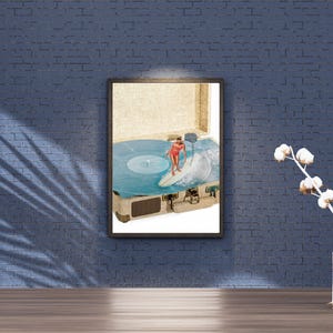 May include: A framed wall art print featuring a surreal collage of a vintage suitcase open to reveal a blue vinyl record spinning. A person in a red swimsuit is surfing on a white surfboard atop the record, with a wave crashing on the side.