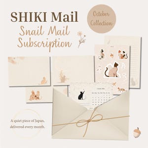 Puede incluir: Un set de papelería con el texto SHIKI Mail Snail Mail Subscription October Collection, que incluye sobres color crema, papel rayado, pegatinas de gatos y una tarjeta de calendario con un gato negro, todo en tonos tierra neutros.