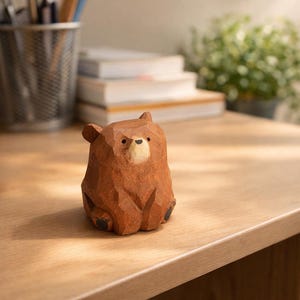 Pode incluir: Uma estatueta de urso de madeira entalhada &agrave; m&atilde;o com uma superf&iacute;cie texturizada detalhada. O urso &eacute; castanho com um focinho de cor mais clara e olhos e patas pretas. A estatueta est&aacute; numa superf&iacute;cie de madeira.
