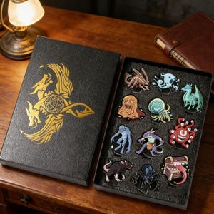 May include: A black box with a gold dragon design, open to reveal a set of colorful fantasy creature pins. The pins include a variety of monsters and creatures, perfect for fans of tabletop games.