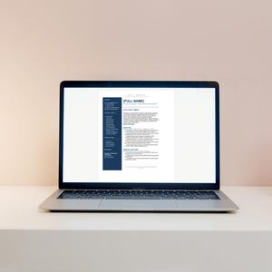 May include: A silver laptop displaying a resume template with a blue sidebar and white document. The screen shows text including "[FULL NAME]" and various sections for contact information, skills, and experience. The laptop is on a white surface.