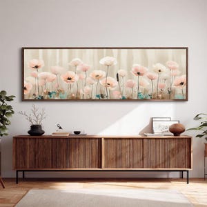 May include: A framed floral art print featuring a field of pink and white poppies against a neutral background. The artwork is displayed above a wooden cabinet with a ribbed design. The cabinet has a dark finish and is supported by black legs.