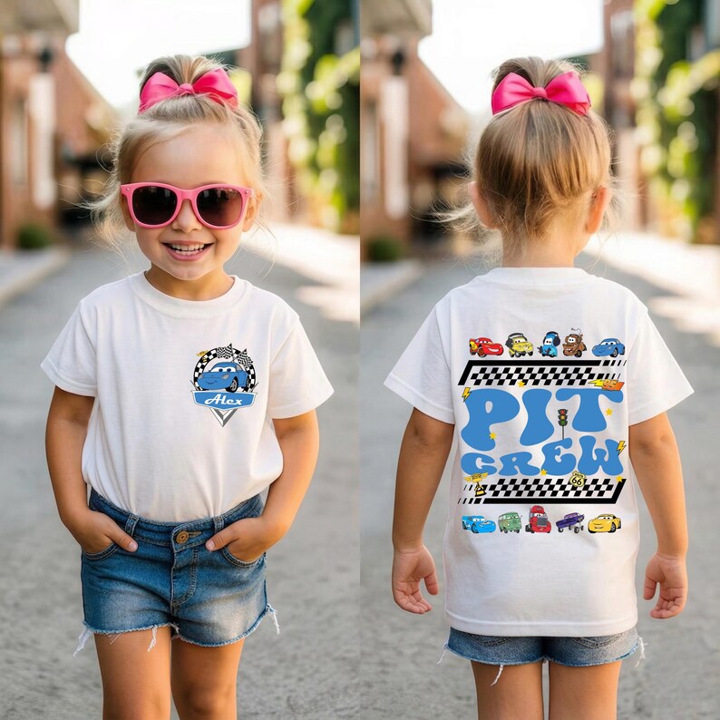 Puede incluir: Camiseta blanca con un gr&aacute;fico de coche de carreras azul y el nombre "Alex". La parte trasera de la camiseta presenta las palabras "Pit Crew" en azul, junto con varias ilustraciones de coches y un dise&ntilde;o de bandera a cuadros.