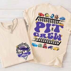 Puede incluir: Dos camisetas beige con gr&aacute;ficos tem&aacute;ticos de coches. Una camiseta presenta un coche morado con banderas y el nombre "Alex". La otra camiseta tiene "PIT CREW" en morado con ilustraciones de coches y un dise&ntilde;o de bandera a cuadros.