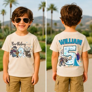 May include: A beige t-shirt with a colorful graphic featuring characters and the text "Birthday Boy" on the front. The back of the shirt displays the name "William" and the number "5" with snowflake accents, and more character graphics.
