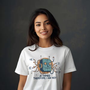 Pode incluir: Camiseta branca com um desenho de cabeça de robô de desenho animado em azul e laranja, cercada por fios e tomadas. O texto "AI THINKS THEREFORE I AM NOT" está impresso abaixo. A camiseta é usada por uma pessoa.
