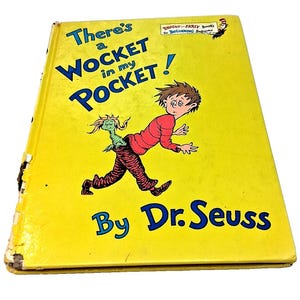 May include: A vintage hardcover book titled "There's a Wocket in my Pocket!" by Dr. Seuss. The cover is bright yellow with blue text and a cartoon illustration of a boy and a green creature. The book is part of the "Bright & Early Books for Beginning Beginners" series.