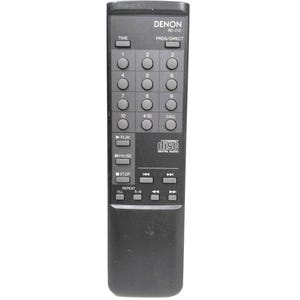 Puede incluir: Un mando a distancia negro Denon RC-212 que presenta un teclado numérico, botones de reproducción para play, pausa, stop y navegación de pistas, junto con funciones de repetición y el logotipo Compact Disc Digital Audio en el frente.