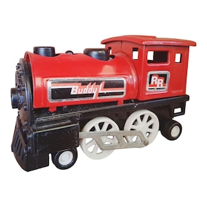 May include: A red and black toy train with white wheels. The train has the text "Buddy L" on the side and "RR" on the back. The toy train is a classic design.