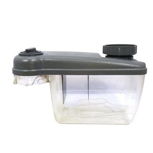 May include: A clear plastic reservoir container with a dark grey lid, featuring a circular screw-top cap on the right side and a small black button on the left. The rectangular base is transparent, showing internal components and a vertical divider.