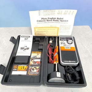 May include: A General Electric HELP! 40-channel mobile CB radio set in a black plastic carrying case. Includes a handheld radio unit with an orange accent, a magnetic mount antenna, coiled power cord, and printed manuals titled Plain English Rules.