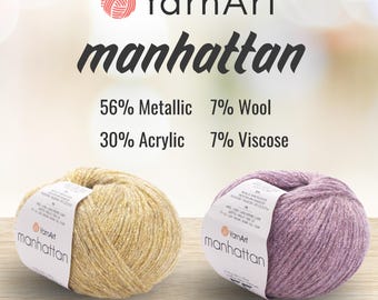 Pode incluir: Dois novelos de fio YarnArt Manhattan, um dourado e um roxo, cada um com uma etiqueta de papel branco. O texto diz YarnArt manhattan, 56% Metálico, 30% Acrílico, 7% Lã, 7% Viscose, com os códigos de cor 902 e 909 visíveis abaixo.