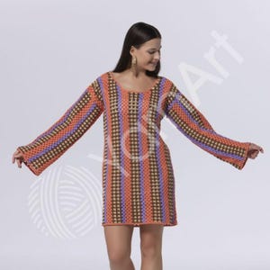 Pode incluir: Um vestido de croch&ecirc; de manga comprida com listras verticais em cores alternadas laranja, marrom e roxo claro. A pe&ccedil;a possui decote redondo e mangas largas e evas&ecirc;, confeccionada com um padr&atilde;o de ponto aberto em todo o corpo.