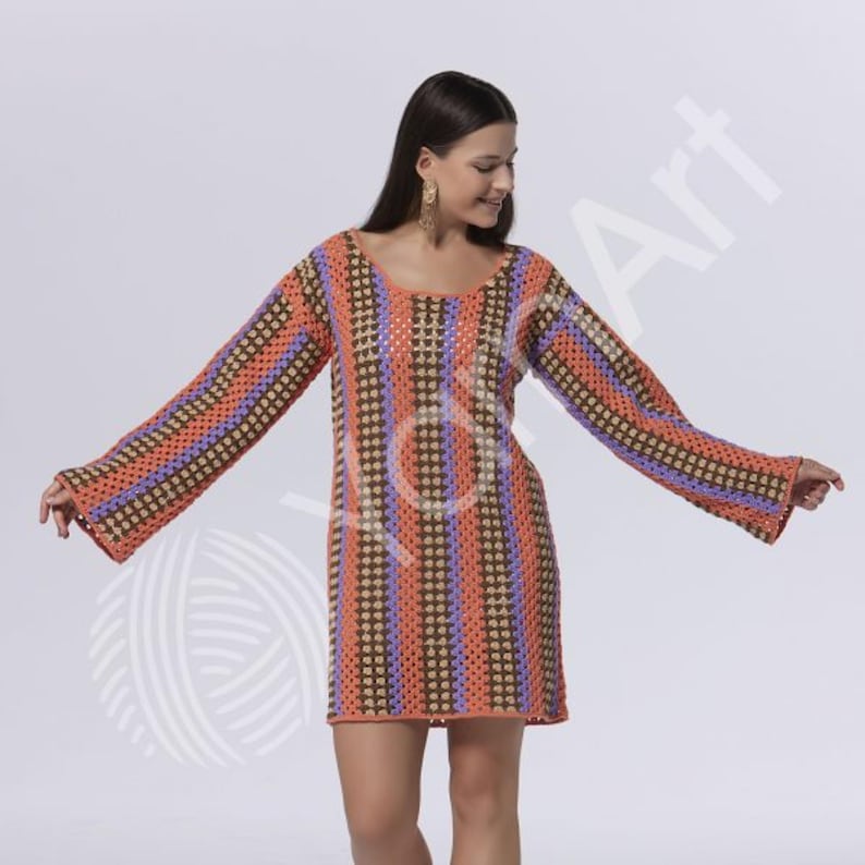 Pode incluir: Um vestido de croch&ecirc; de manga comprida com listras verticais em cores alternadas laranja, marrom e roxo claro. A pe&ccedil;a possui decote redondo e mangas largas e evas&ecirc;, confeccionada com um padr&atilde;o de ponto aberto em todo o corpo.