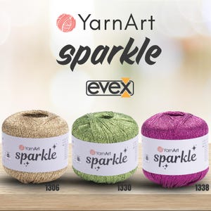 May include: Three balls of YarnArt Sparkle yarn in gold, green, and magenta. Each ball has a white paper label with the text YarnArt sparkle and two small star icons. The brand logo YarnArt and the text sparkle and evex appear above the yarn.