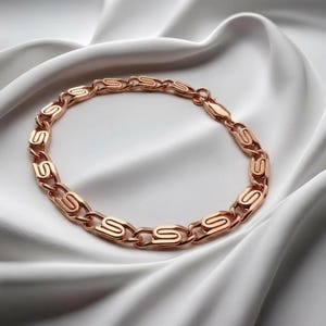 May include: A rose gold chain bracelet featuring a series of repeating S-shaped links connected by small circular rings. The metal has a polished, reflective finish, and the bracelet includes a secure lobster claw clasp mechanism for closure.