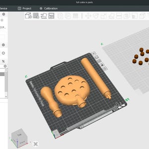 Puede incluir: Una pantalla de ordenador muestra una interfaz de software de modelado 3D. La pantalla muestra varios objetos impresos en 3D de color naranja, incluyendo un objeto redondo con agujeros, dos asas y una pieza cil&iacute;ndrica larga. Tambi&eacute;n son visibles esferas marrones adicionales.