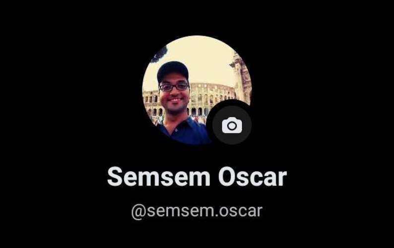 May include: A circular profile picture featuring a person wearing a dark cap and blue shirt, positioned in front of a large stone structure. Below the image, the text reads Semsem Oscar followed by the handle @semsem.oscar on a black background.