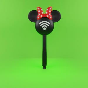 Puede incluir: Bolígrafo negro con diseño de Minnie Mouse, con orejas negras, un lazo rojo con lunares blancos y un símbolo de WiFi. El bolígrafo tiene un mango largo y negro y está sobre un fondo verde brillante.
