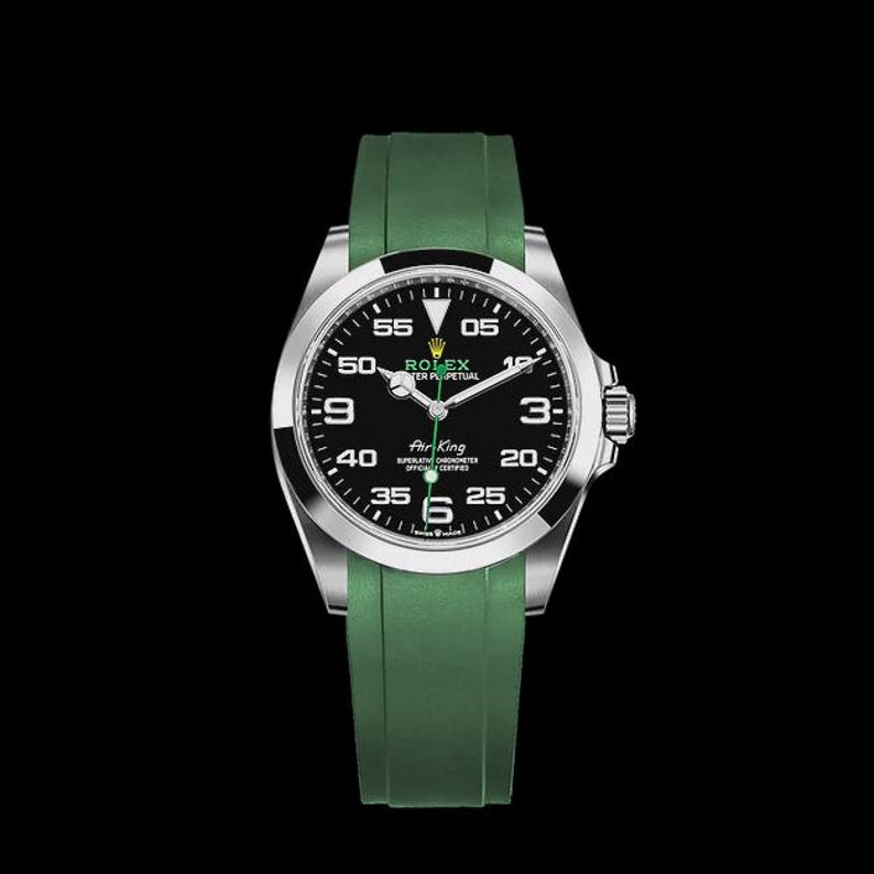 May include: A stainless steel Rolex Air King watch with a black dial and green rubber strap. The watch face displays the time with white numerals and hands. The watch has a silver bezel and a crown on the right side.