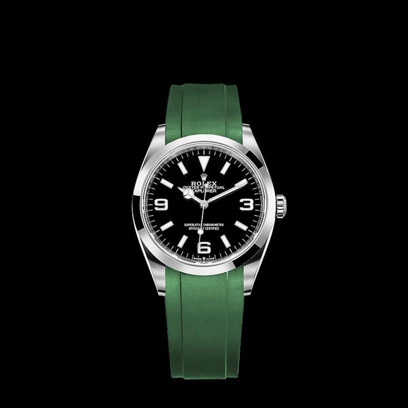 K&ouml;nnte beinhalten: Eine silberne Armbanduhr mit schwarzem Zifferblatt und wei&szlig;en Ziffern. Die Uhr hat ein gr&uuml;nes Kautschukarmband. Das Zifferblatt zeigt den Markennamen und das Modell.