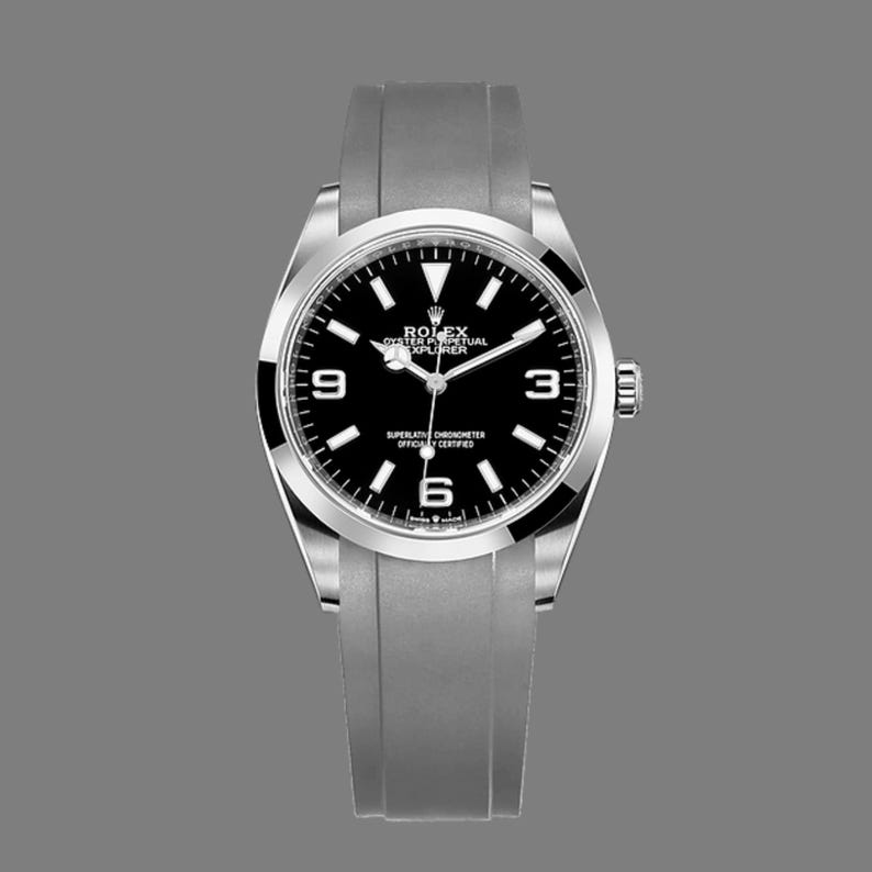 K&ouml;nnte beinhalten: Eine silberfarbene Armbanduhr mit schwarzem Zifferblatt und grauem Armband. Das Zifferblatt hat wei&szlig;e Stundenmarkierungen und Zeiger, mit den Ziffern 3, 6 und 9. Es ist ein Rolex Explorer Modell.