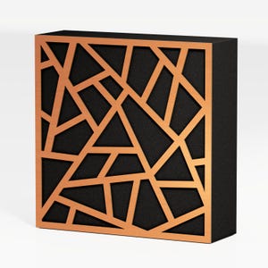 Puede incluir: Una caja cuadrada negra con un diseño geométrico color cobre en la parte delantera. El diseño está formado por líneas y formas interconectadas, creando un patrón abstracto. La caja tiene un acabado mate.