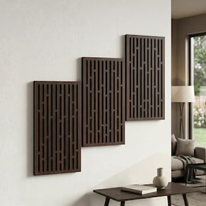 May include: Three dark brown wooden wall panels with vertical cut-out designs are mounted on a white wall. The panels are rectangular and vary in size, creating a staggered arrangement. The panels add a modern, decorative element to the space.