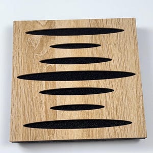 May include: A square wooden panel with a light brown wood grain finish. The panel features six horizontal, elongated cutouts filled with black material. The design creates a visually interesting pattern, suitable for home decor or acoustic treatment.