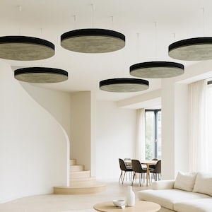 May include: Contemporary interior with multiple circular ceiling lights. Each light has a light-coloured centre and a black border. The lights are suspended in a living room with a white sofa and large windows. The room has a minimalist design.