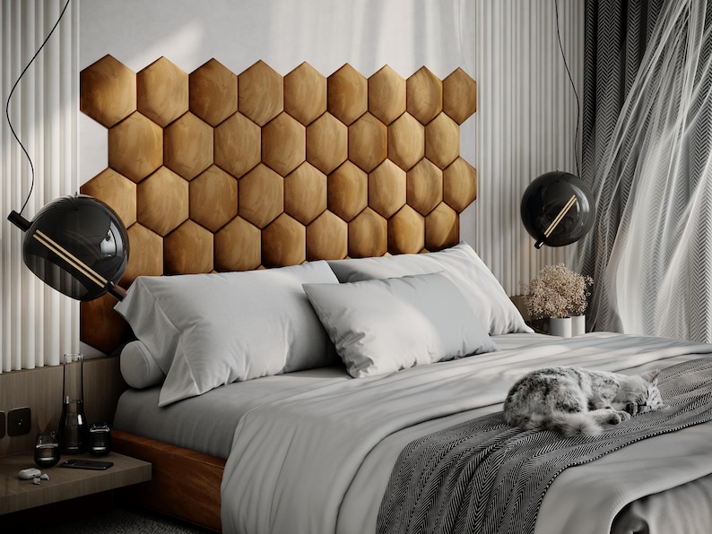 Puede incluir: Un dormitorio moderno con una cama con un gran cabecero geom&eacute;trico de color miel. La cama est&aacute; hecha con ropa de cama gris claro y una manta gris oscuro. Un gato est&aacute; durmiendo en la cama. L&aacute;mparas colgantes negras en forma de globo cuelgan del techo.
