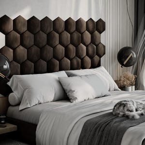 Puede incluir: Un dormitorio moderno con un cabecero marr&oacute;n oscuro con dise&ntilde;o de panal. La cama est&aacute; hecha con ropa de cama blanca y gris claro, y una manta gris. Dos l&aacute;mparas colgantes negras en forma de globo cuelgan sobre la cama. Un gato est&aacute; durmiendo en la cama.