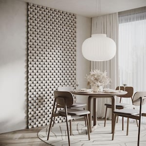 Puede incluir: Un comedor moderno con una mesa redonda de madera y cuatro sillas grises. Una gran lámpara colgante esférica blanca cuelga sobre la mesa. Un panel decorativo de pared y una alfombra estampada completan la escena.