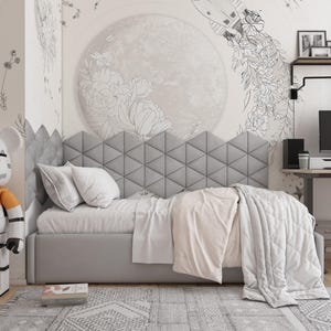 May include: A modern bedroom scene featuring a gray bed with a geometric headboard, white bedding, and a patterned rug. The wall has a large moon and floral design. A toy figure stands to the left.