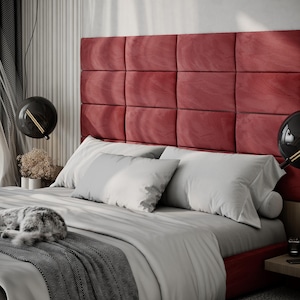 May include: A modern bedroom with a red upholstered headboard, gray bedding, and decorative black globe pendant lights. A gray and white cat is curled up on the bed. The room has a minimalist design.