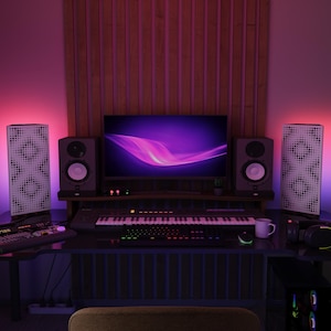 Könnte beinhalten: Ein modernes Heimstudio-Setup mit einem Computermonitor, der eine lila Grafik anzeigt. Der Schreibtisch verfügt über eine Tastatur, Lautsprecher und ein Mischpult. Der Raum wird mit violetter und rosa Umgebungsbeleuchtung beleuchtet, wodurch eine lebendige Atmosphäre entsteht.