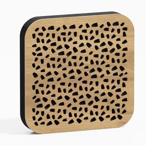 May include: Square wooden panel with rounded corners, featuring a light brown surface with numerous irregularly shaped black cutouts. The edges are framed with a black border, creating a contrasting visual effect.