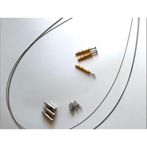 May include: A selection of picture hanging hardware, featuring silver metal cable grippers, yellow wall anchors with screws, and small silver springs. Two long, thin, grey metal cables are also visible, arranged on a white surface.