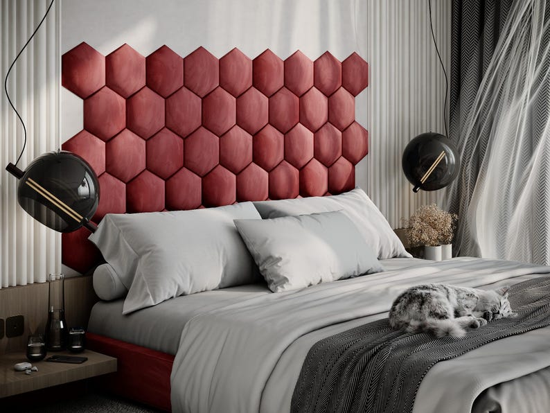 Puede incluir: Un dormitorio moderno con una cama con un cabecero rojo y geom&eacute;trico. La cama est&aacute; hecha con s&aacute;banas y almohadas blancas, y una manta gris. Un gato est&aacute; durmiendo en la cama. Luces colgantes negras en forma de globo cuelgan del techo.