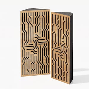 Op de afbeelding: Twee hoge, driehoekige akoestische panelen met een lichthouten voorzijde en een donker, verdiept printplaatpatroon. De panelen hebben een massief donkergrijs zijprofiel en een platte bovenkant, ontworpen voor verticale plaatsing in een hoek.