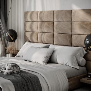 May include: A modern bedroom with a large bed featuring a tufted headboard and gray bedding. Two black globe pendant lights hang above the bed. A gray and white cat is curled up on the bed.