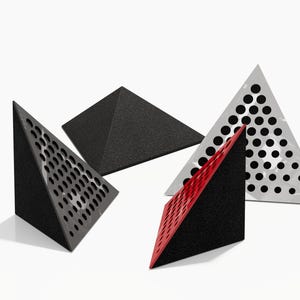 May include: Four geometric triangular objects in black, gray, and red. Two triangles have a perforated design, one with a red face. The other two are solid, one black and one gray. All are on a white background.