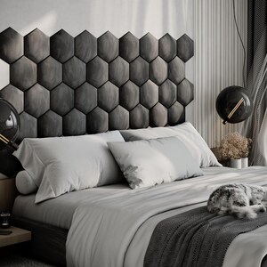 Puede incluir: Un dormitorio moderno con una cama con ropa de cama y almohadas blancas, una manta gris estampada y un cabecero gris compuesto por paneles hexagonales. Un gato duerme en la cama. Dos l&aacute;mparas colgantes negras en forma de globo cuelgan del techo.