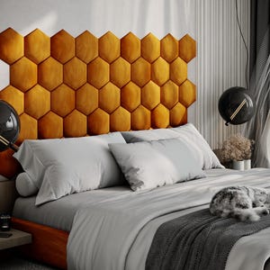 Puede incluir: Un dormitorio moderno con una cama con un cabecero con forma de panal de color mostaza. La cama est&aacute; hecha con ropa de cama blanca y gris, y un gato gris est&aacute; durmiendo en la cama. L&aacute;mparas colgantes negras en forma de globo cuelgan del techo.