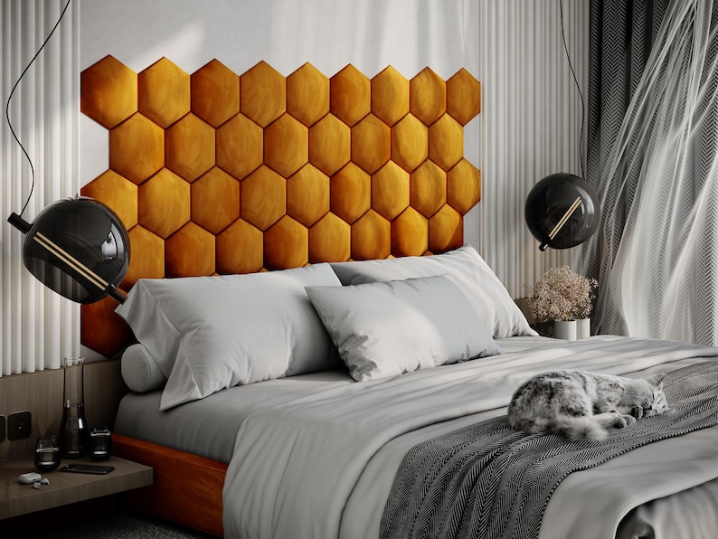 Puede incluir: Un dormitorio moderno con una cama con un cabecero con forma de panal de color mostaza. La cama est&aacute; hecha con ropa de cama blanca y gris, y un gato gris est&aacute; durmiendo en la cama. L&aacute;mparas colgantes negras en forma de globo cuelgan del techo.