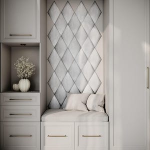 May include: A built-in cabinet unit with a seating area. The unit features white cabinets with gold-toned hardware, a diamond-patterned wall panel, and a cushioned bench with pillows. A vase with flowers sits on a shelf.